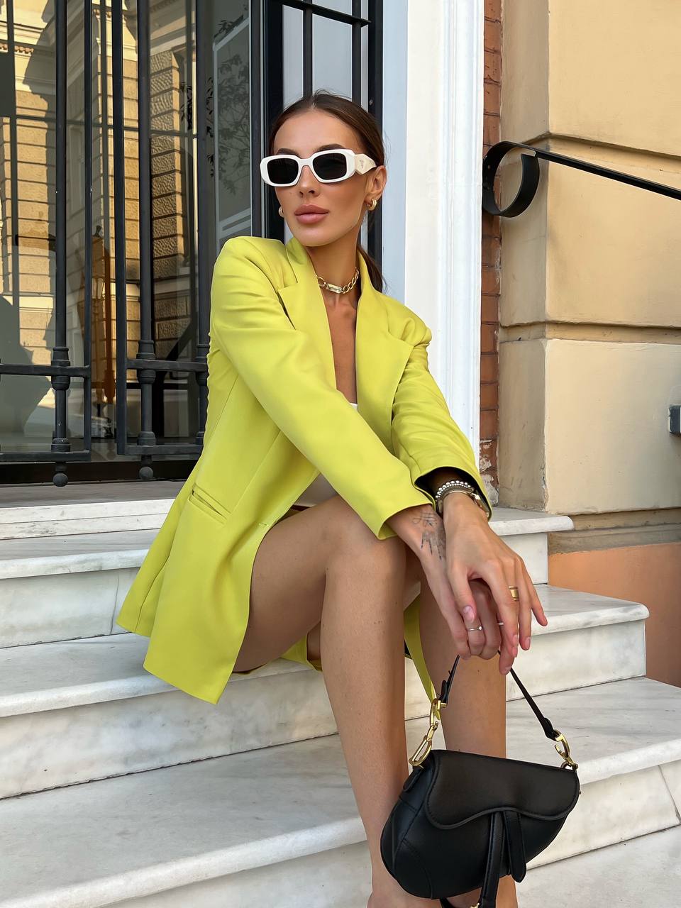 Woman in a bright yellow blazer sitting on steps outdoors