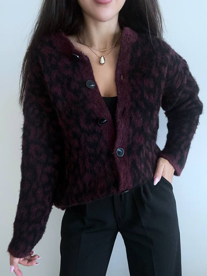 Person wearing a dark purple leopard print jacket against a plain background