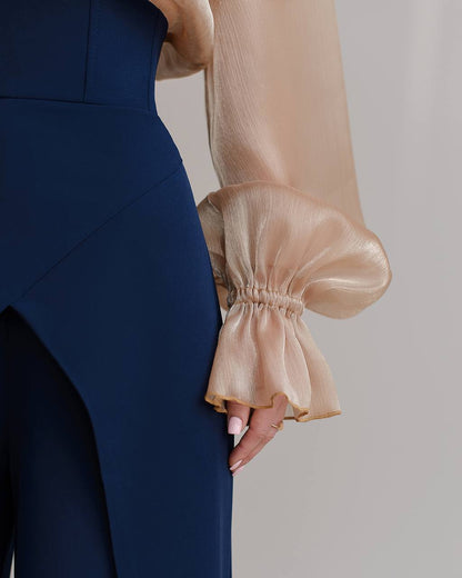 Navy blue dress with beige sheer sleeves on a neutral background