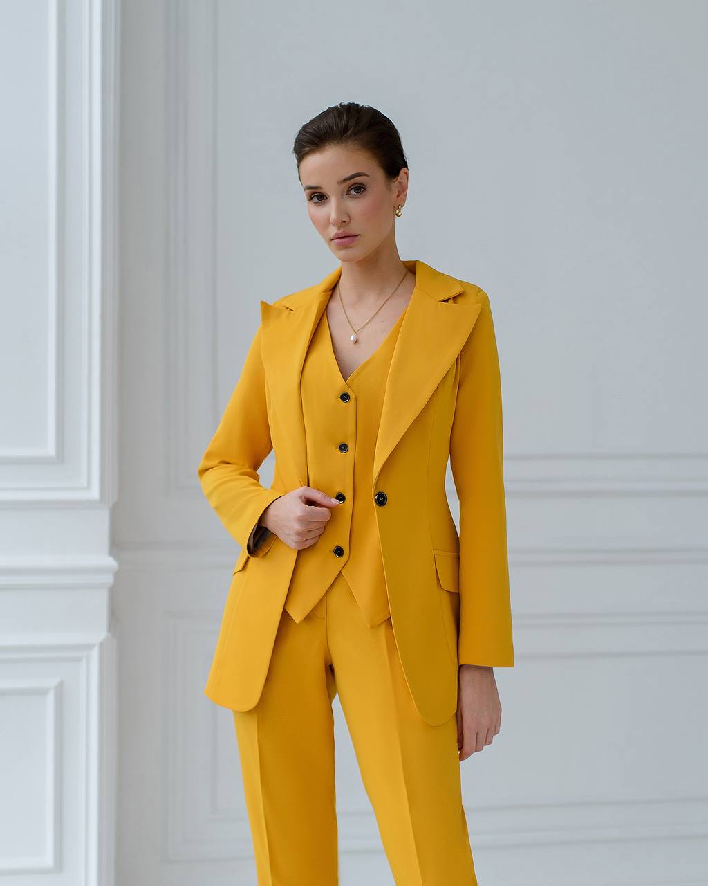 Woman wearing a yellow suit against a white wall