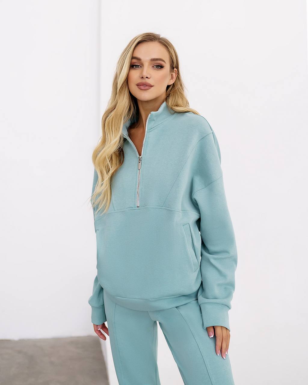 Woman wearing a light blue tracksuit against a white background