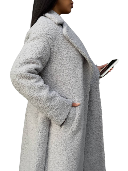 Person wearing a long gray teddy coat on a white background