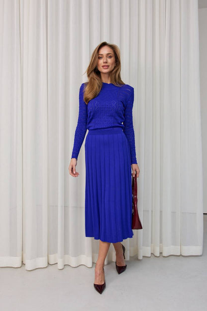 Woman wearing a blue outfit standing in front of white curtains