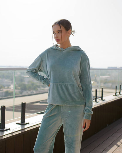 Woman wearing a light blue tracksuit on a rooftop with a cityscape background