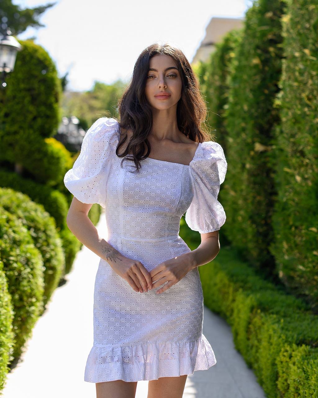 Woman in a white dress standing in a garden with greenery