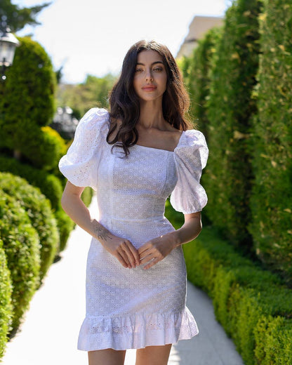 Woman in a white dress standing in a garden with greenery