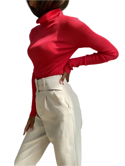 Person wearing a red turtleneck and white pants on a white background