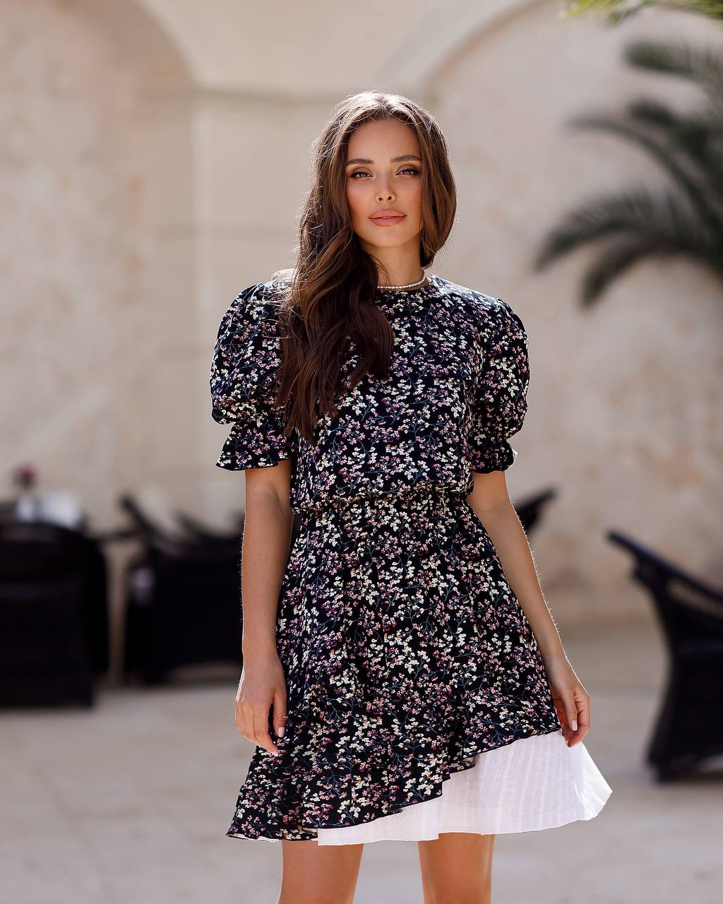 Woman wearing a floral dress standing outdoors with a blurred background