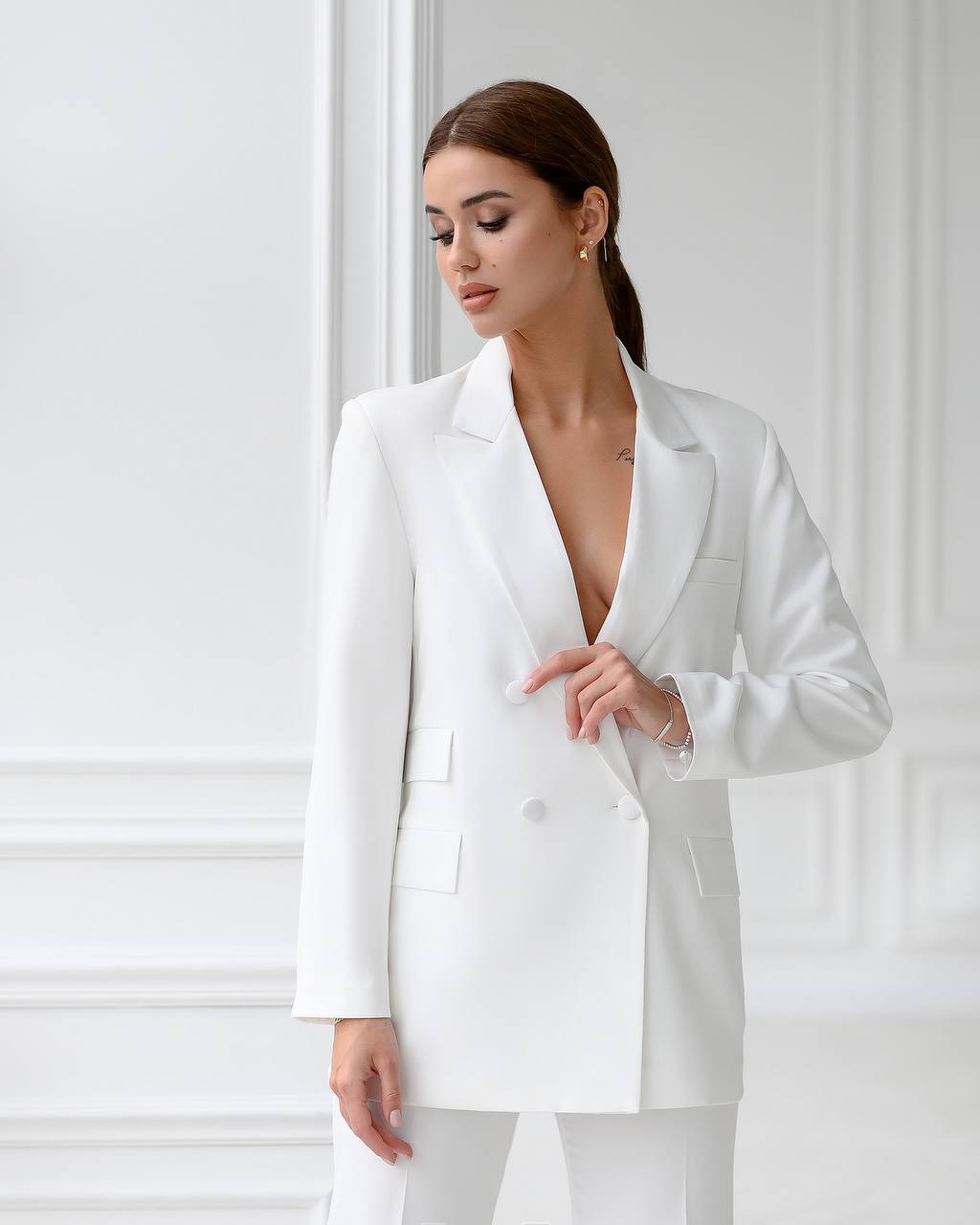 Woman wearing a white blazer against a plain background