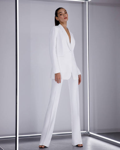 Woman wearing a white suit standing in a futuristic, metallic room.
