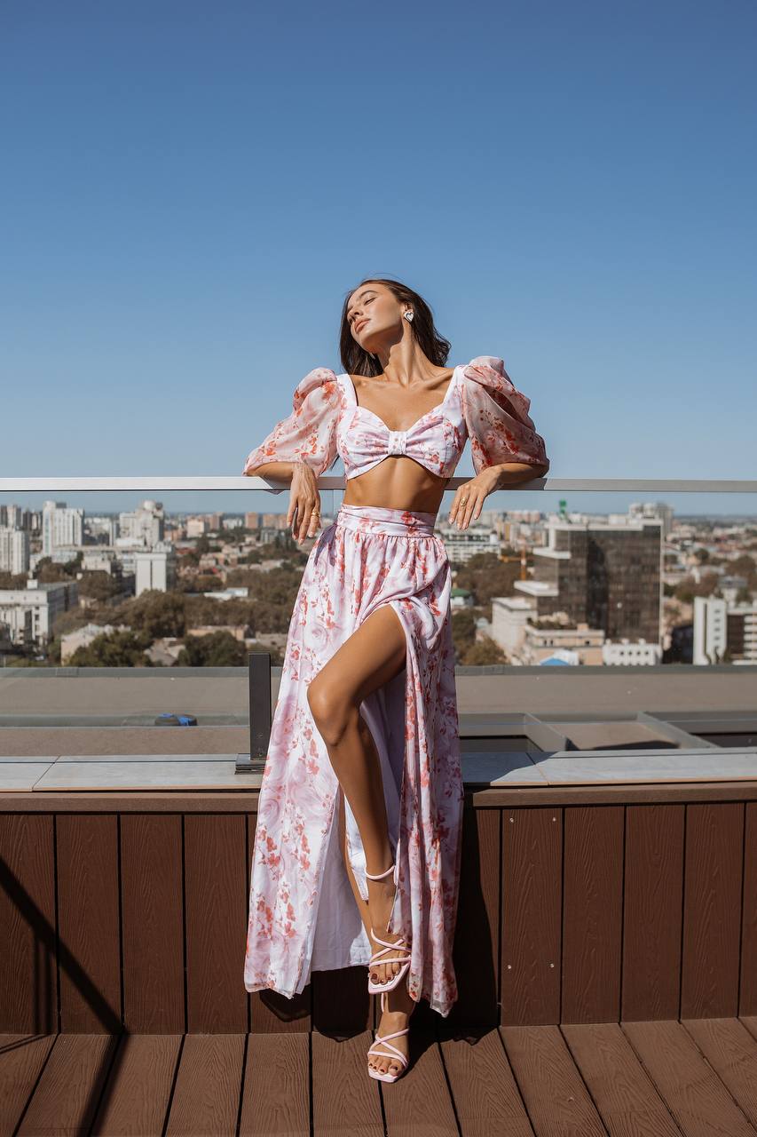 Woman in a floral dress standing on a rooftop with a cityscape in the background
