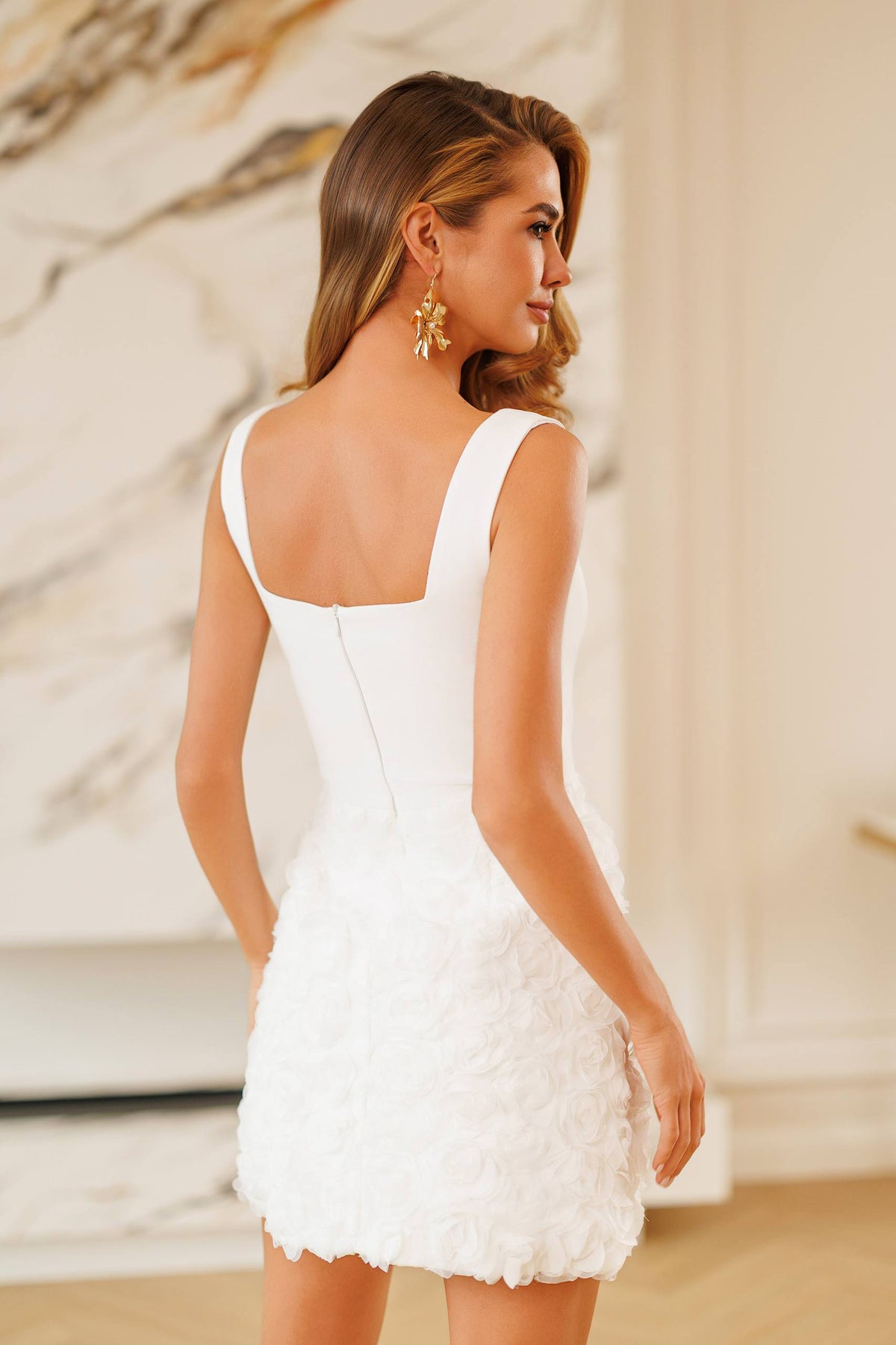 Woman wearing a white dress with a marble wall background