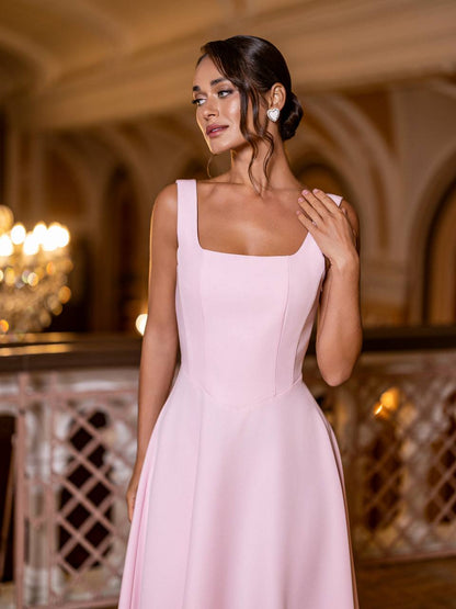Woman in a pink dress standing in an elegant indoor setting with chandeliers.