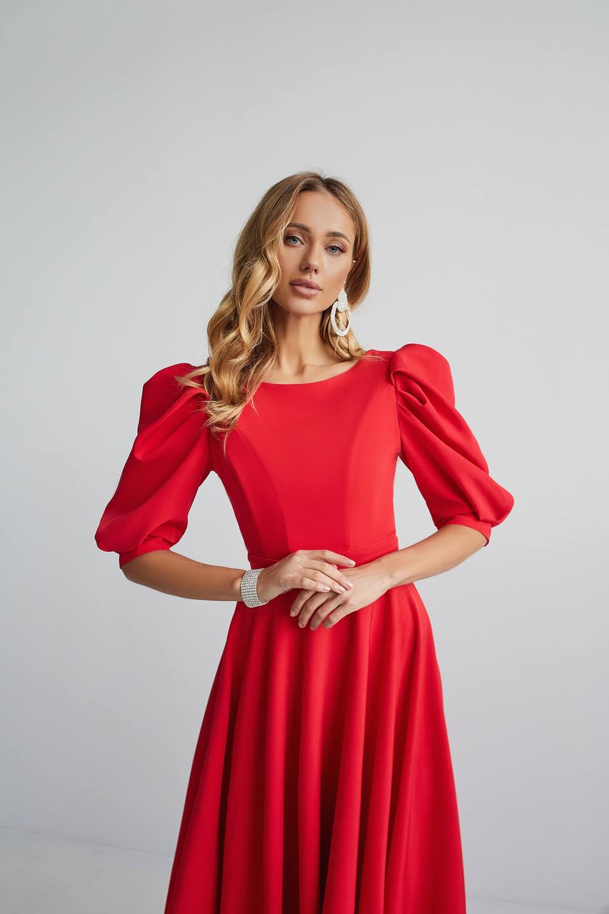 Woman wearing a red dress with puff sleeves against a light gray background