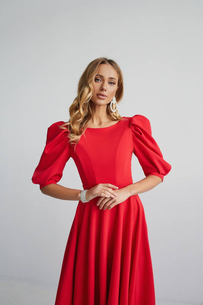 Woman wearing a red dress with puff sleeves against a light gray background