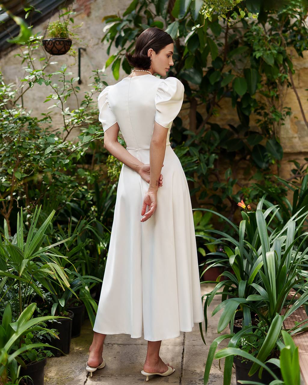 Woman in a white dress standing among green plants