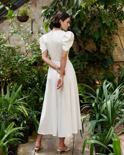 Woman in a white dress standing among green plants