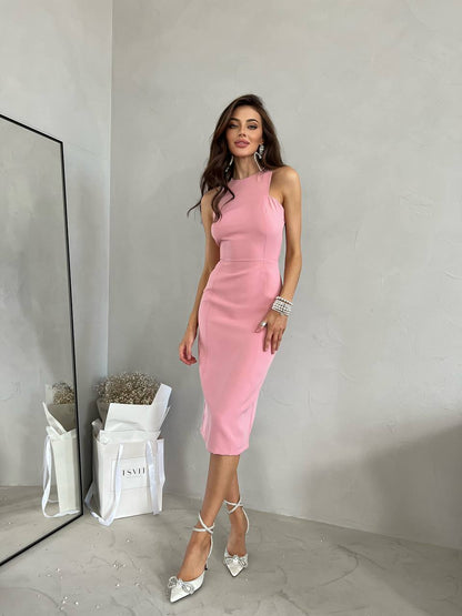 Woman in a pink dress standing in a minimalistic room with a mirror and plant.