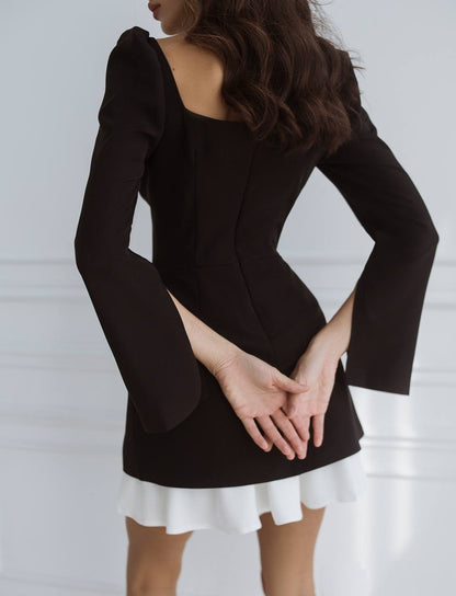 Person wearing a black dress with a white hem on a light gray background