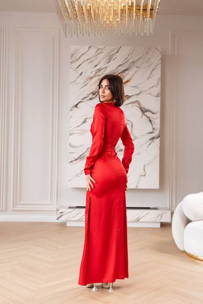 Woman in a red dress standing in an elegant room with marble wall art and chandelier.