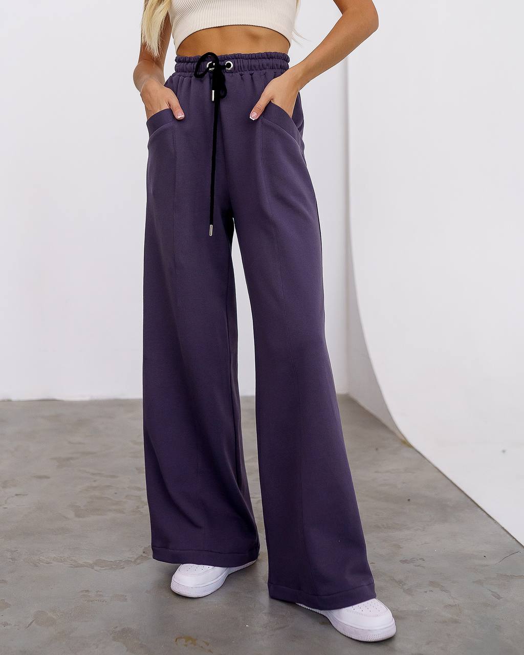 Person wearing purple wide-leg pants with a white background