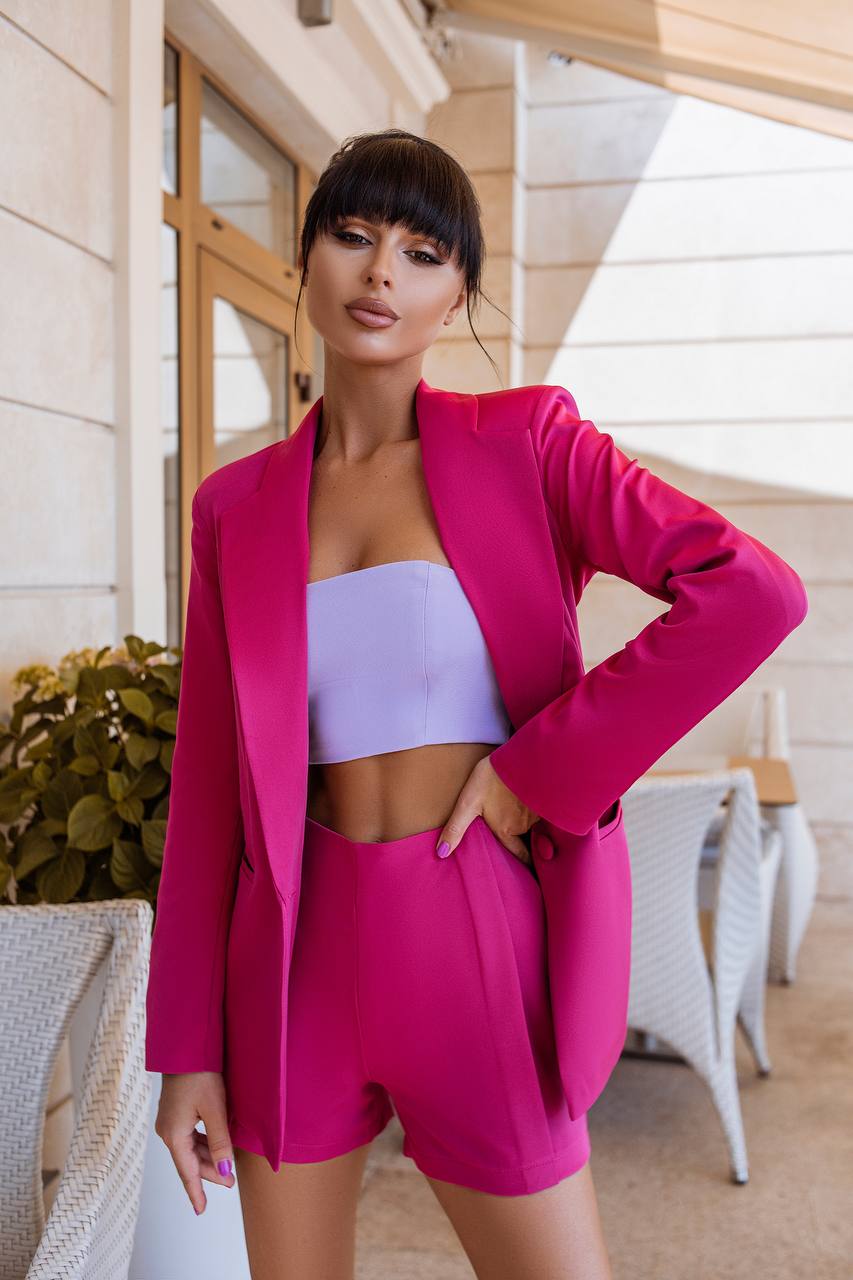 Woman in a bright pink outfit standing outdoors.