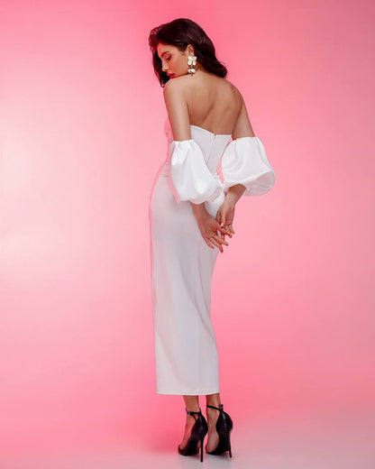 Woman wearing a white off-shoulder dress with puffed sleeves against a pink background