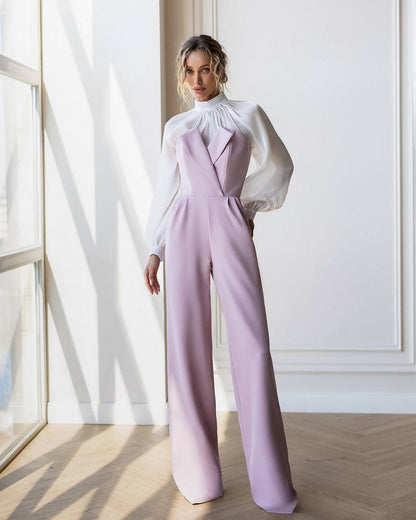 Woman wearing a lavender jumpsuit with a white blouse in a bright room.