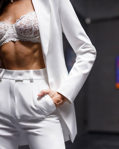 Person wearing a white lace bralette and high-waisted white pants with a white blazer.