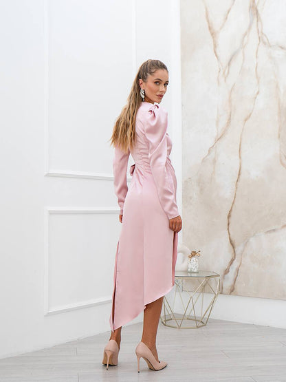 Woman in a pink dress standing in a room with marble wall and glass table.