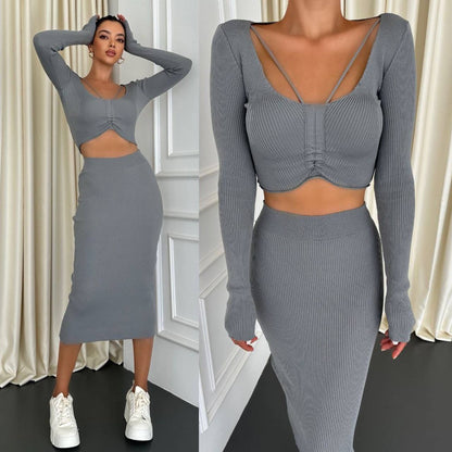 Woman wearing a gray ribbed two-piece outfit with long sleeves and a skirt, standing against a white wall.