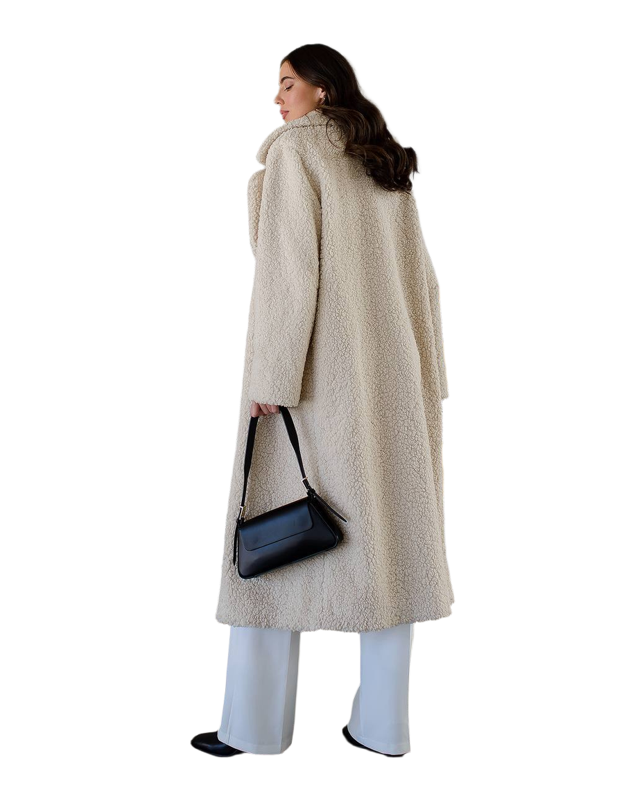 Woman wearing a long beige coat holding a black handbag on a white background