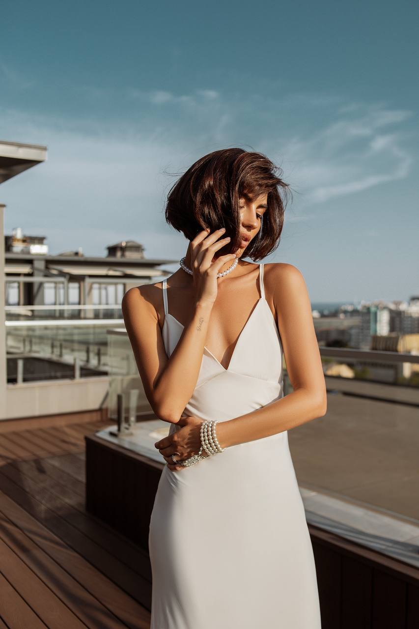 Woman in a white dress on a rooftop with a cityscape background