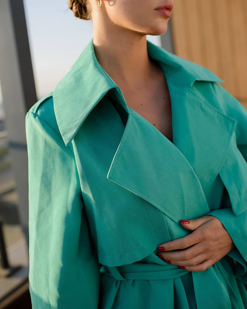 Person wearing a teal trench coat with a blurred background