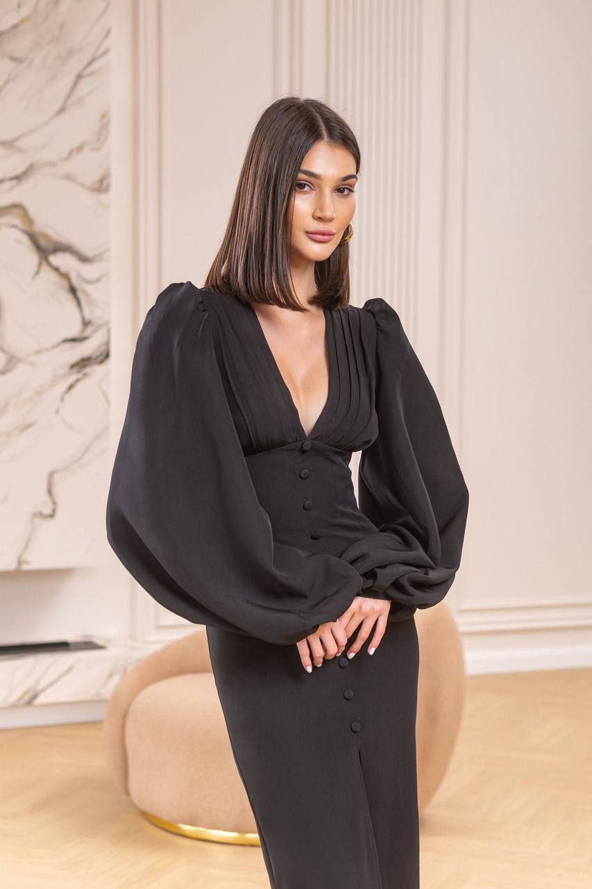 Woman wearing a black dress with puffed sleeves in an elegant interior setting