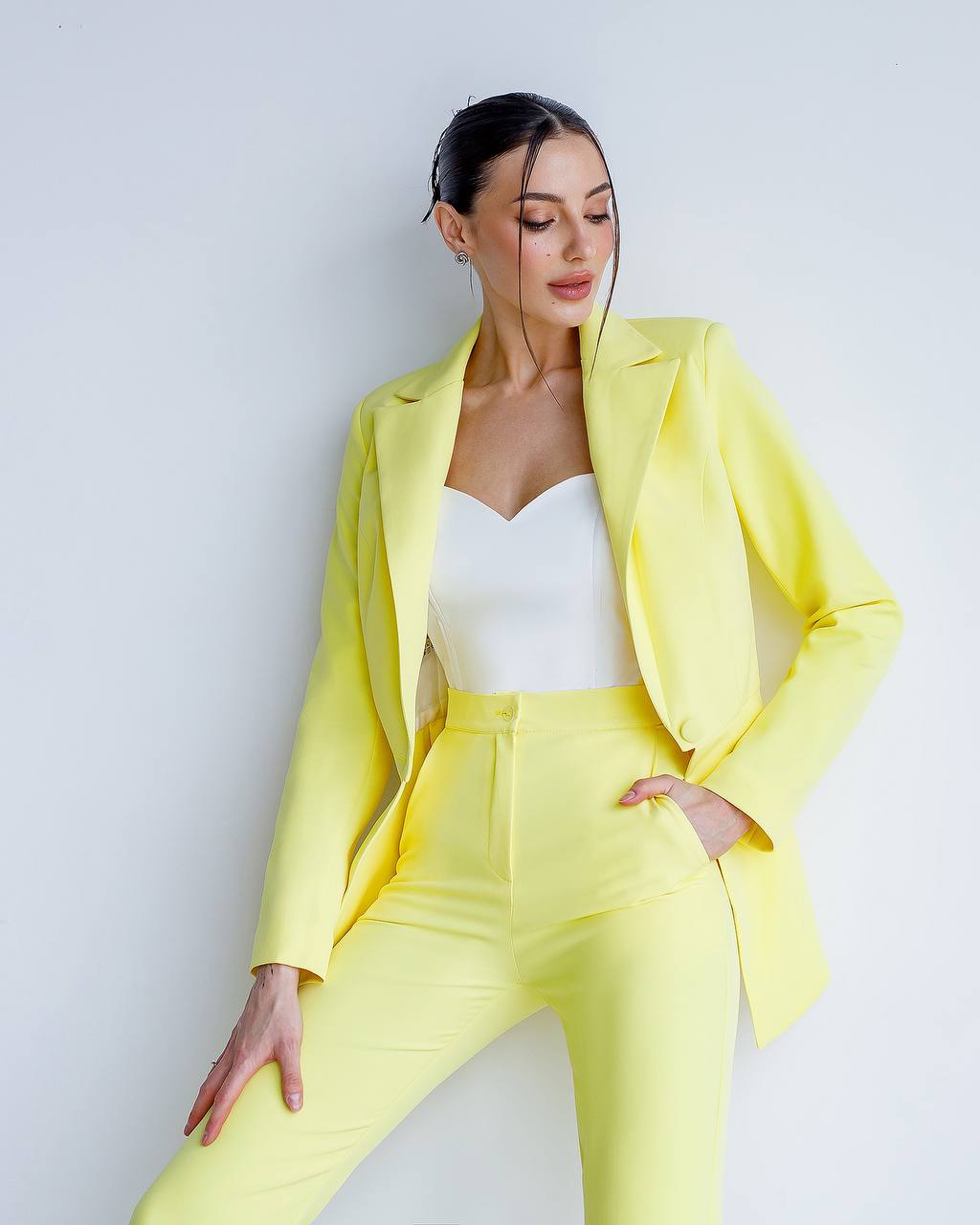 Woman wearing a bright yellow suit against a white background