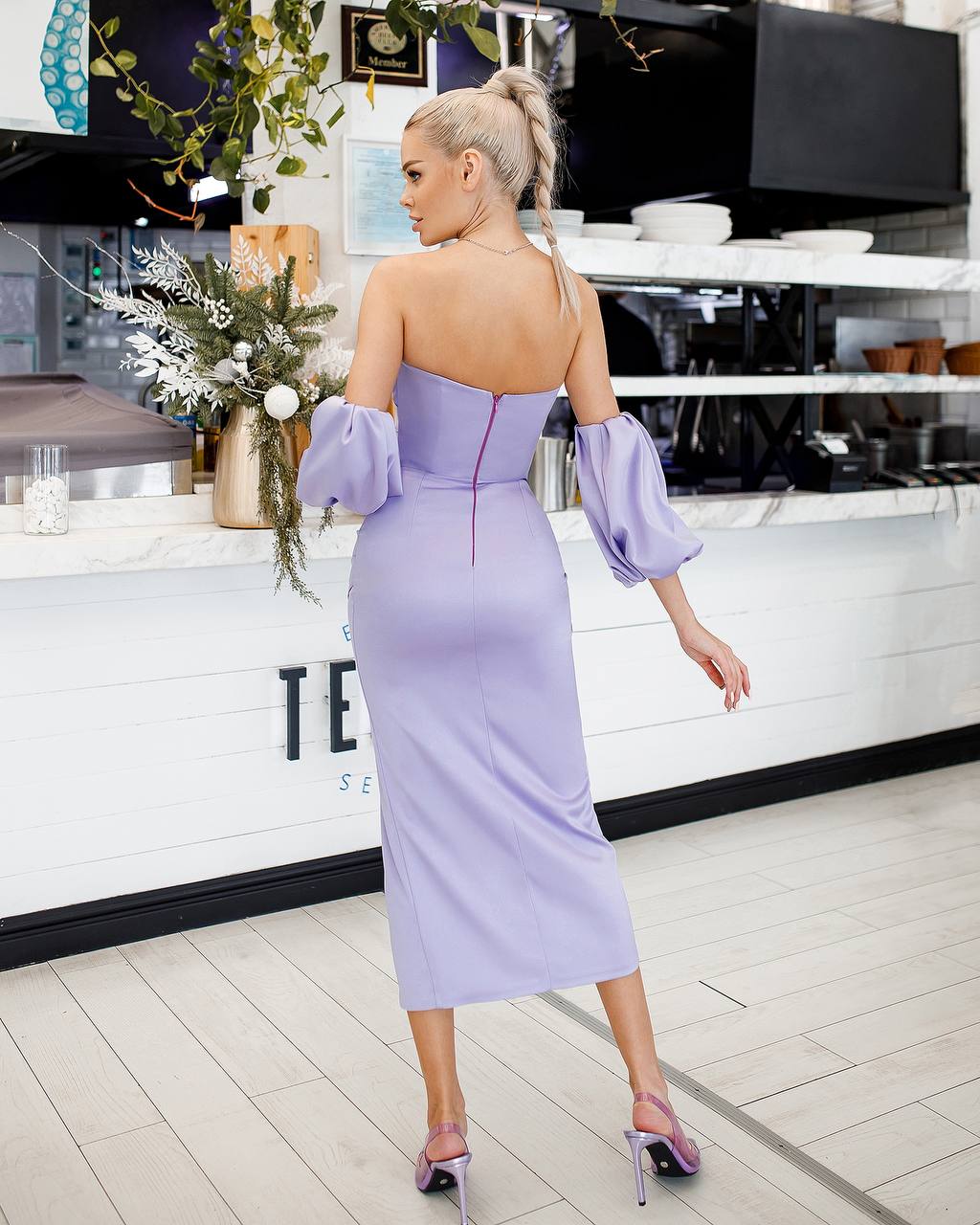 Woman in a lavender dress standing in a modern kitchen.