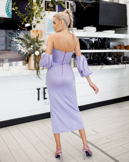 Woman in a lavender dress standing in a modern kitchen.