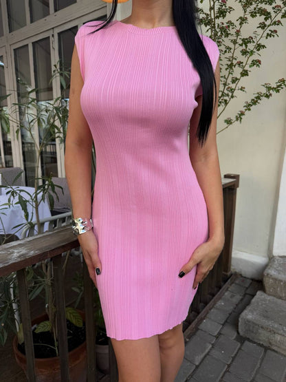 Person wearing a pink sleeveless dress standing outdoors.