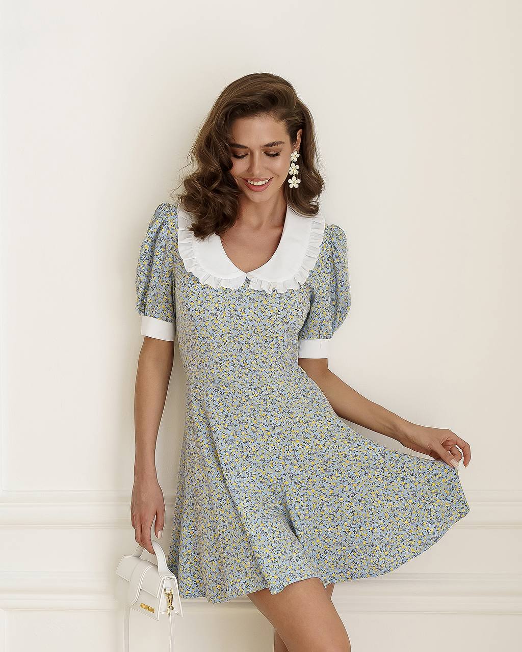 Woman wearing a floral dress with a white collar against a light background