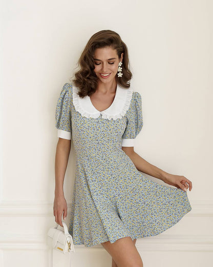 Woman wearing a floral dress with a white collar against a light background