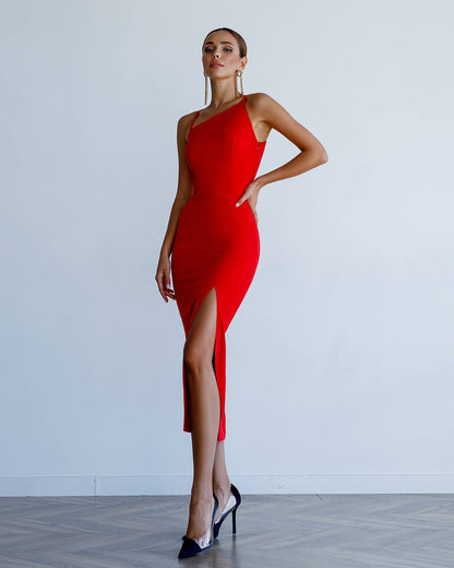 Woman wearing a red one-shoulder dress with a slit, standing against a white background.