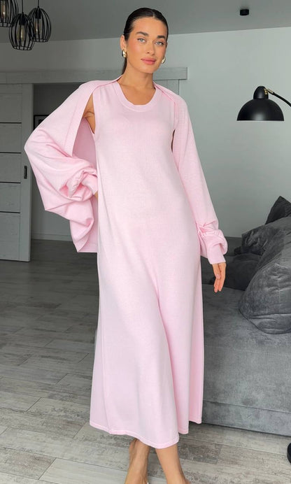 Woman wearing a light pink dress in a room with gray walls and a gray sofa.