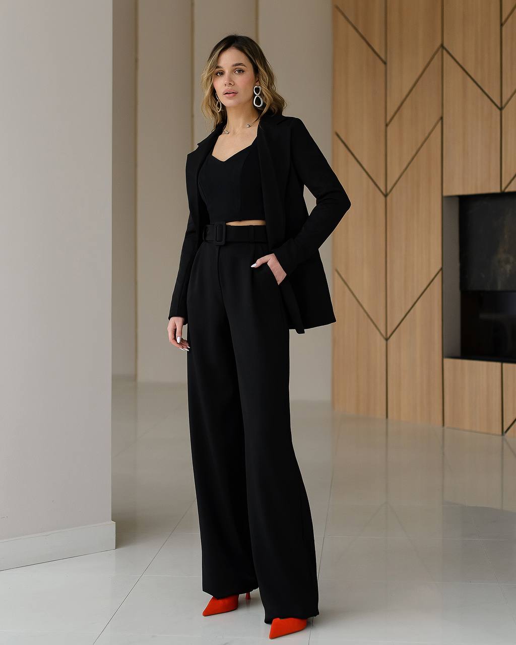Woman in a black outfit standing in a modern interior setting