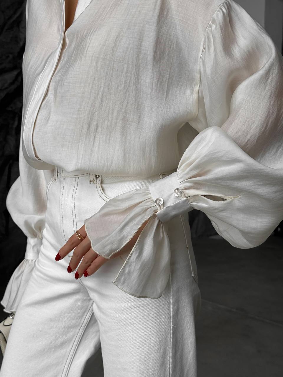 White outfit with puffed sleeves and high-waisted pants on a blurred background