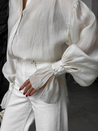 White outfit with puffed sleeves and high-waisted pants on a blurred background