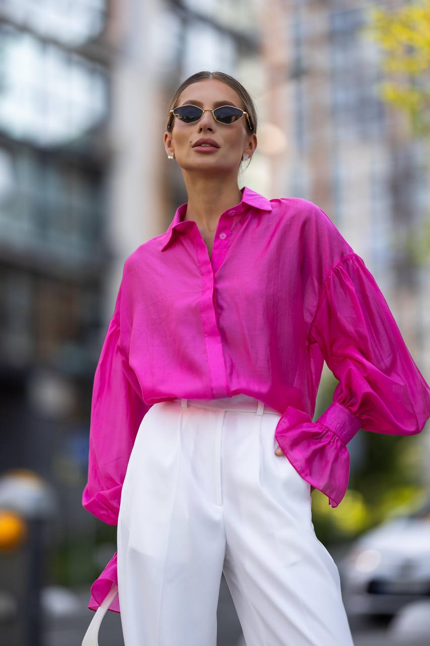 Woman wearing a bright pink shirt and white pants in an urban setting