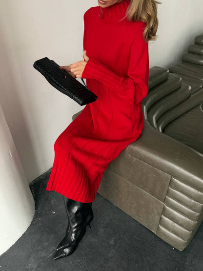 Person wearing a red dress and black boots sitting on a gray couch.