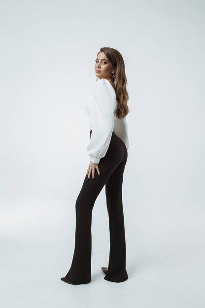 Woman wearing a white blouse and black flared pants on a white background