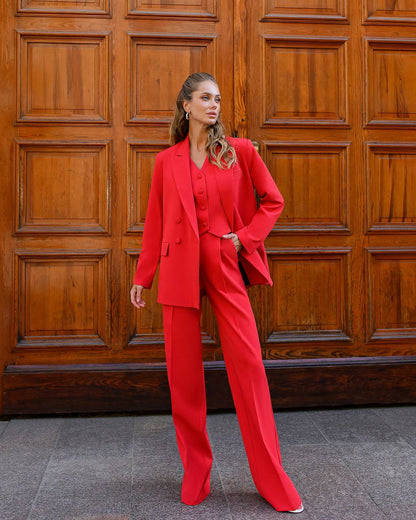 Woman in a red suit standing in front of a wooden door